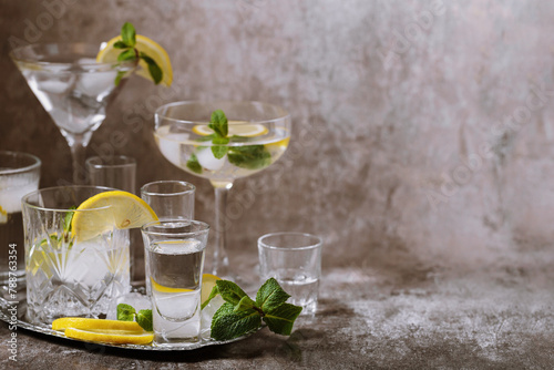 Various glasses on silver tray filled with cold drinks with ice, lemon, mint