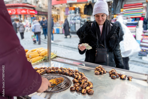 A women with hat buying corn on the street. Street food.