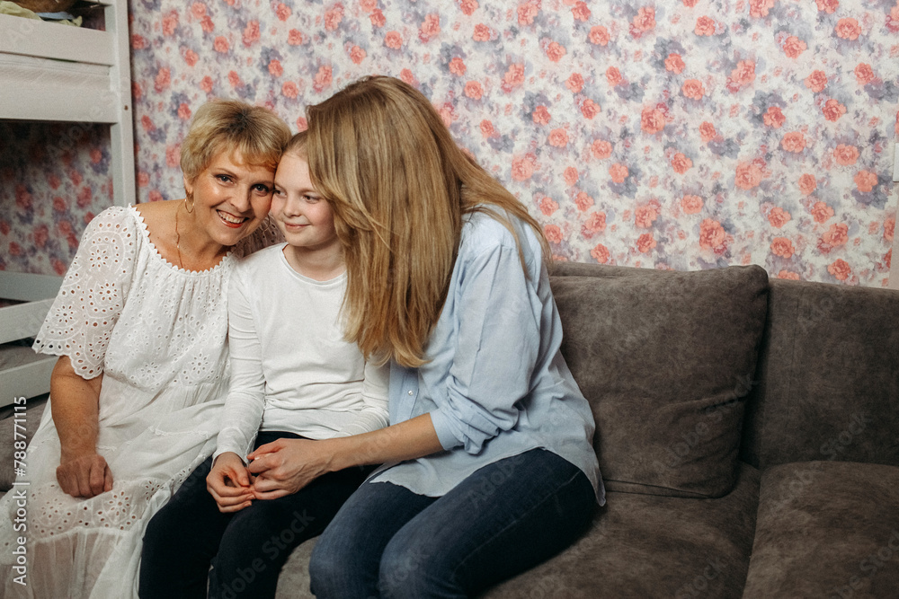 Two women and a child of different generations are sitting on the sofa. Two women and a child of different generations are sitting on the sofa.