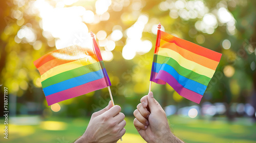 Close up of male hands holding rainbow flags as a symbol of Pride parade.
