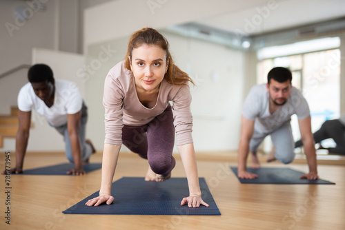 Concentrated sporty young woman doing intense bodyweight workout in fitness studio, performing mountain climber exercise in plank pose..