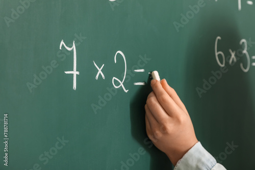 Girl writing on chalkboard during lesson in classroom, closeup