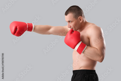 Muscular male bodybuilder in boxing gloves on grey background © Pixel-Shot