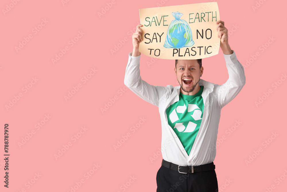 Enthusiastic young man in t-shirt with recycling sign holding poster with text SAVE EARTH SAY NO TO PLASTIC on pink background. Ecology concept Enthusiastic young man in t-shirt with recycling sign holding poster with text SAVE EARTH SAY NO TO PLASTIC on pink background. Ecology concept