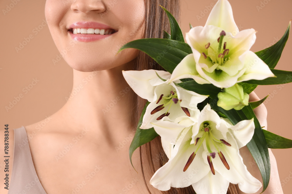 Beautiful young happy woman with white lily flowers on beige background, closeup