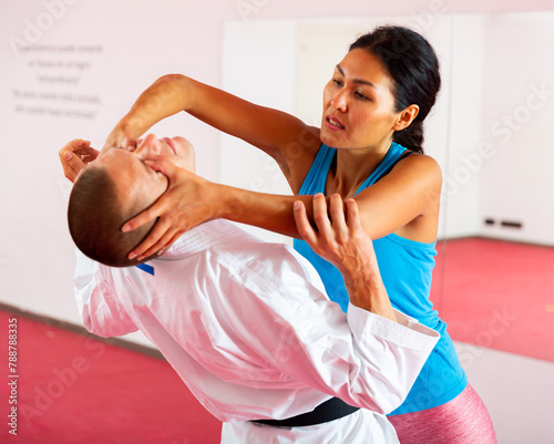 Woman and trainer train painful hold on self-defense course in a boxing gym