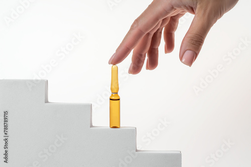 Hand reaching for Aloe extract serum ampoule on steps