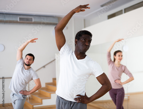 Adult african american man practicing ballet dance moves during group class in choreographic studio