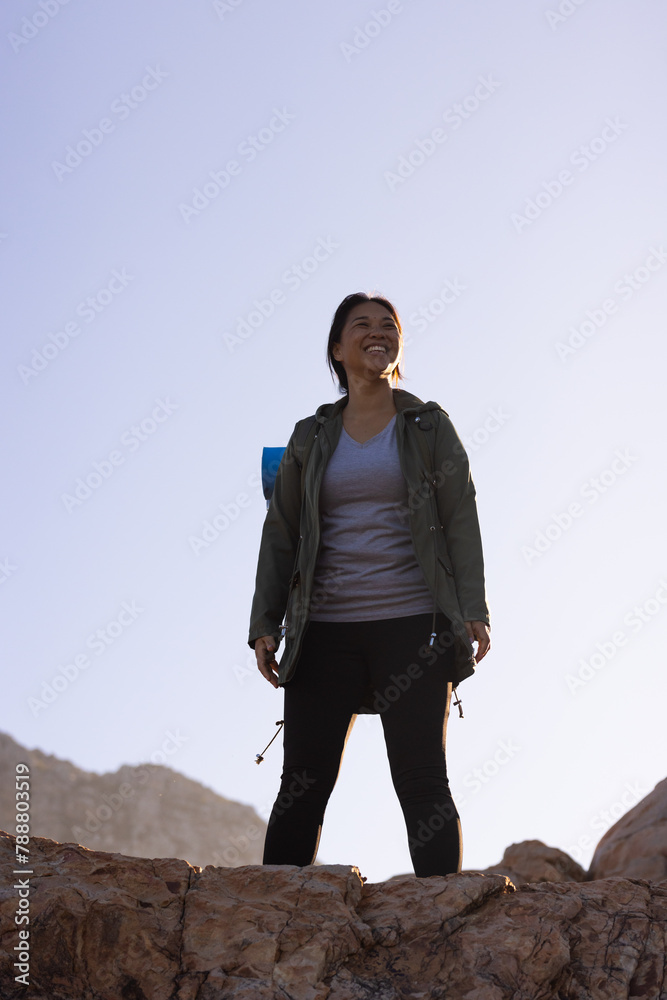 Biracial female hiker standing on a rock, looking up, with copy space Biracial female hiker standing on a rock, looking up, with copy space