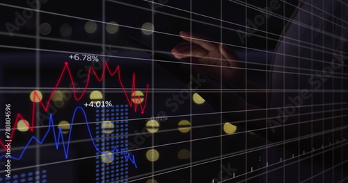 A person wearing dark outfit pointing at a digital graph showing market trends