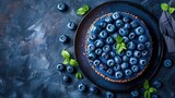 Plate of blueberries with mint on dark textured background
