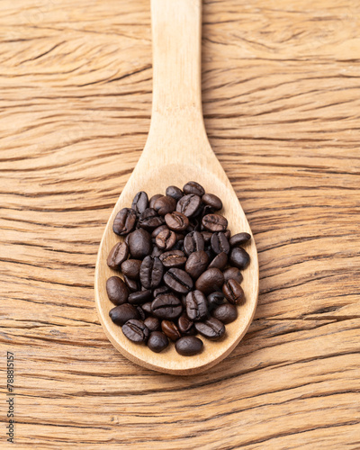 Coffee beans on a spoon over wooden table