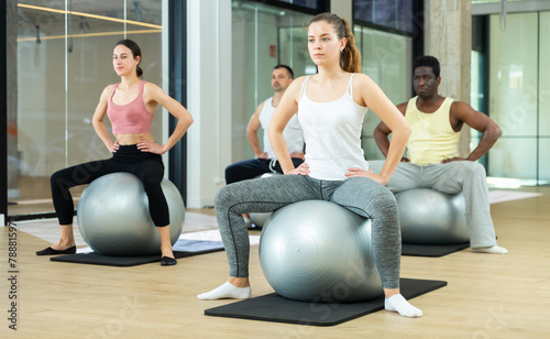 Portrait of young sporty woman during group workout with fitness ball at gym. Healthy lifestyle concept