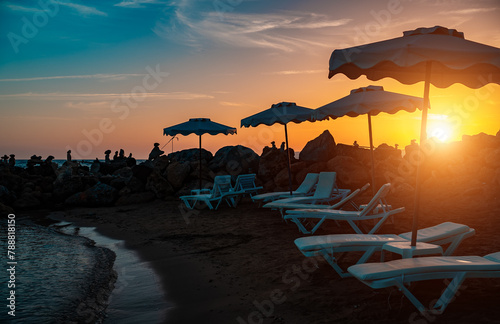 Cozy little sandy beach with sun loungers at sunset.