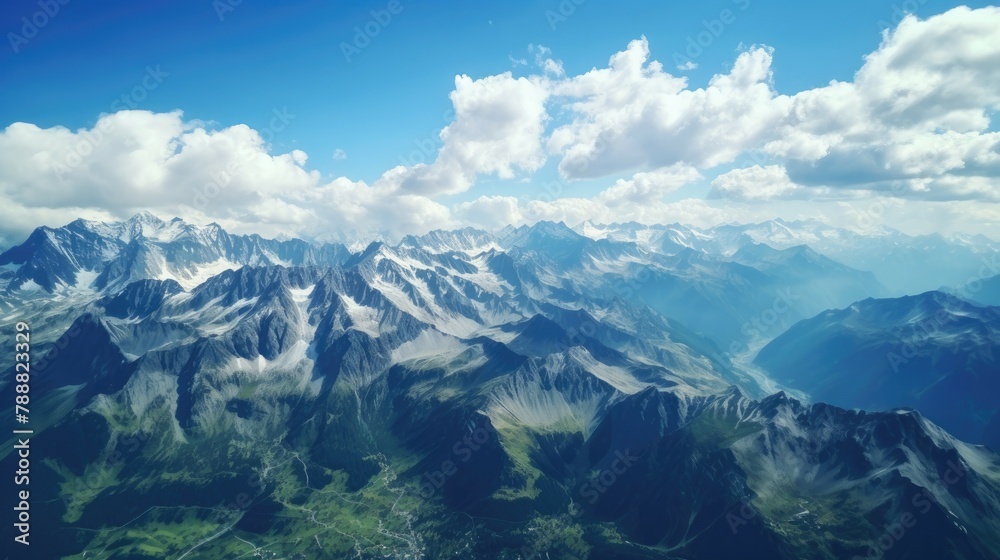 Amazing view of snow-capped mountains from above. The peaks of the mountains are covered in snow, while the valleys are green and lush.
