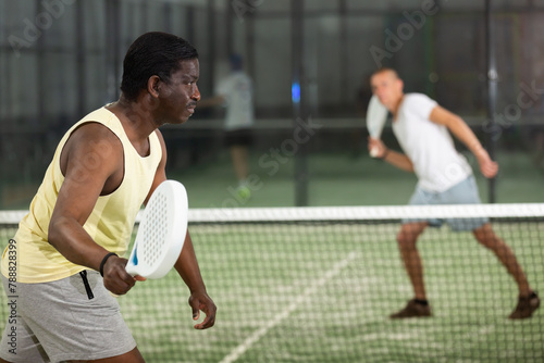 African american man playing paddle tennis on the padel court