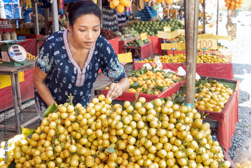 A young woman is standing near a tropical fruit the Burmese grape, in the market, Thailand photo