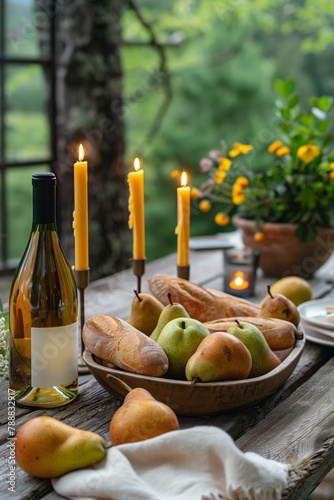 Wine, freshly baked baguette, ripe pears on a wooden outdoor table with candles