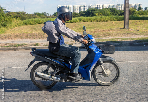 A motorcyclist rides a scooter with a fluttering jacket