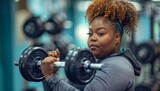 Confident plus-sized woman lifting weights in the gym, focused and determined