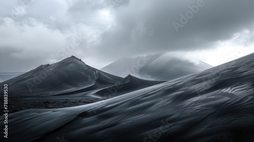 Sculpted black sand dunes against mountain silhouettes under overcast sky