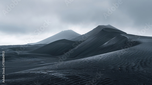 Stark black sand dunes rippling toward a mountain shrouded in misty clouds