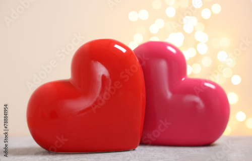 Ceramic hearts on grey table against blurred lights