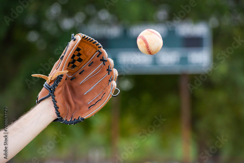 Man's arm and baseball mitt about to catch ball