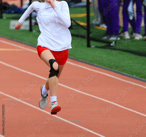 One girl running a sprint race on a track wearing KT tape on her knee