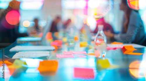 Vibrant but blurred colors of a brainstorming session capturing the energy of a group huddled around laptops and postit notes on a cluttered tabletop. .