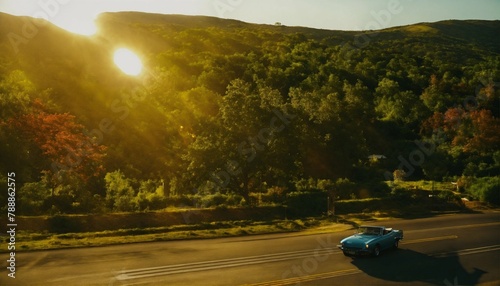 A car gracefully cruises along a winding road as the sun sets in the background, creating a serene late afternoon setting.






