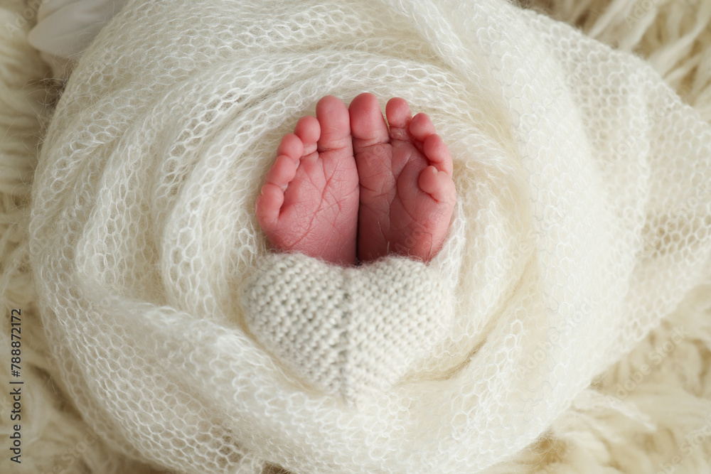 The tiny foot of a newborn baby. Soft feet of a new born in a wool white blanket The tiny foot of a newborn baby. Soft feet of a new born in a wool white blanket