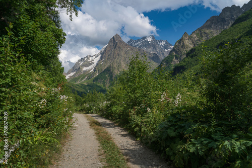 View of the Dombay-Ulgen gorge in the mountains of the North Caucasus and the trail to the Chuchkhur waterfall near the village of Dombay on a sunny summer day, Karachay-Cherkessia, Russia