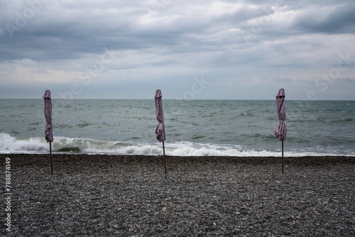A deserted beach with umbrellas on the Sochi coast against the background of the Black Sea, Adler, Krasnodar Territory, Russia