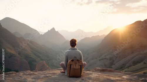 Male traveler sitting in summer mountains at sunset
