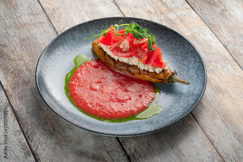 Baked eggplant with cottage cheese and tomatoes in a plate on a wooden background, Italian dish