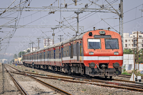 Indian Railways Diesel-Electric Multiple Unit local train exiting out of a wayside station near Pune