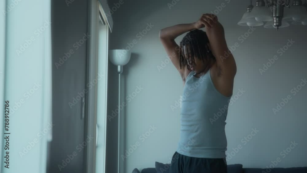 A young man doing stretches next to a window at home. Healthy lifestyle and sport. Slow motion. A young man doing stretches next to a window at home. Healthy lifestyle and sport. Slow motion.