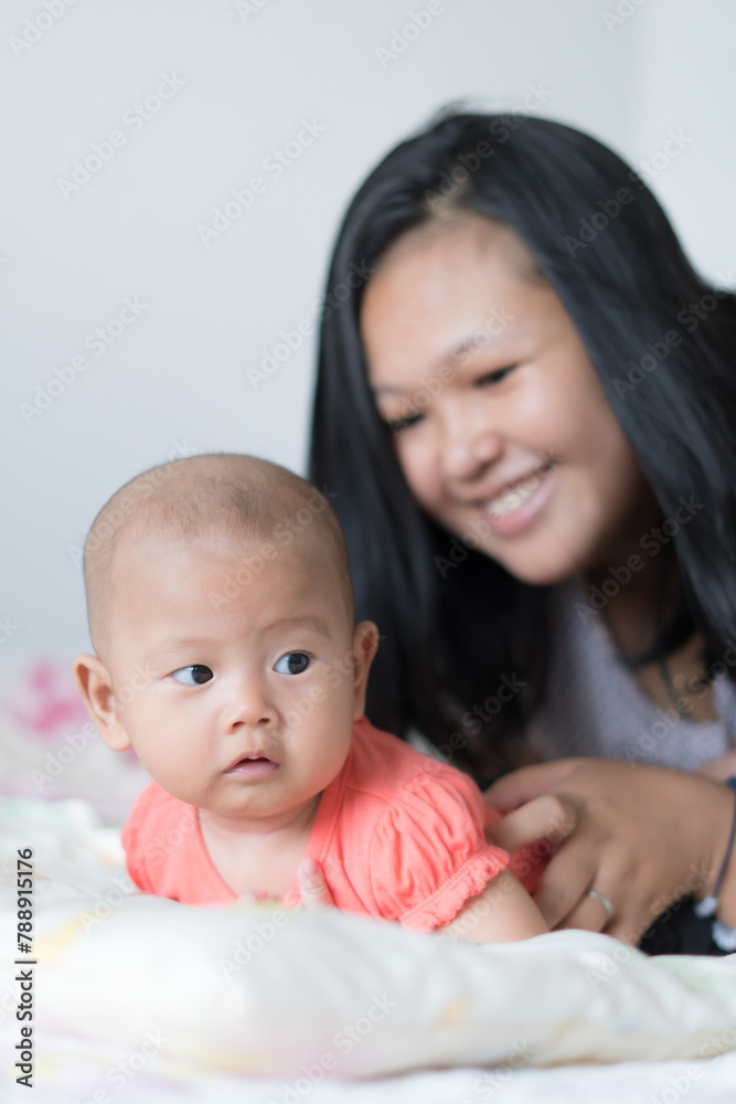 Infant Girl lifting her head with Asian Mother smiling Infant Girl lifting her head with Asian Mother smiling