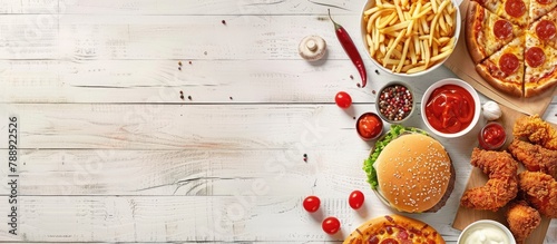 Fast food items like pizza, hamburgers, fried chicken, and side dishes displayed in a corner border banner against a white wooden background, with empty space for text.