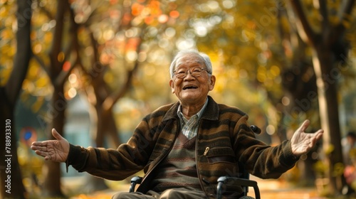Cheerful elderly man sitting in a wheelchair, hands spread out. happy with independent life at the park © ORG