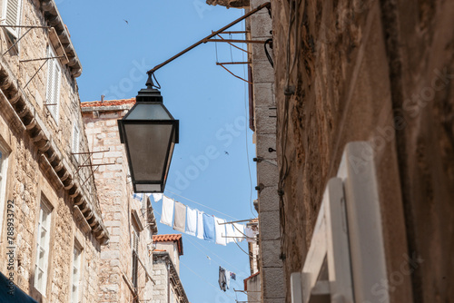 Laundry hanging high above the street between two old stone apartment buildings in European city © Brian Scantlebury