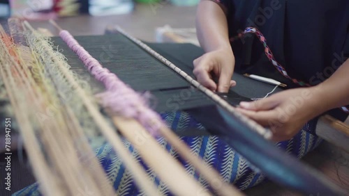 An Indonesian woman weaving traditional lombok fabric, Tenun or Weaving is a technique in the manufacture of fabrics which is made with combining thread lengthwise and transversel. photo