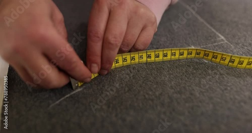 Seamstress uses chalk and measuring tool to mark precise lines photo