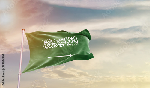 Saudi Arabia flag in waving in beautiful sky with sunlight. photo