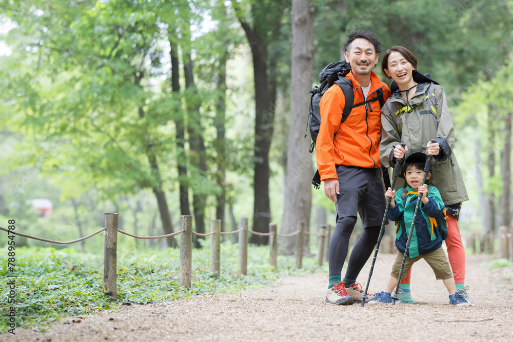 Obraz premium ハイキングする親子 緑の中登山やトレッキングする家族 夏のレジャーやアウトドアのお出かけのイメージ カメラ目線
