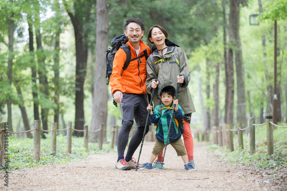 Fototapeta premium ハイキングする親子 緑の中登山やトレッキングする家族 夏のレジャーやアウトドアのお出かけのイメージ カメラ目線