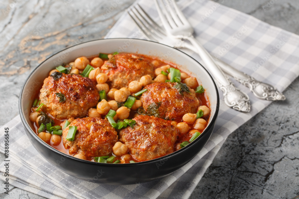 Mediterranean food Lamb meatballs served with chickpeas, tomato and green onions close-up in a bowl on the table. Horizontal