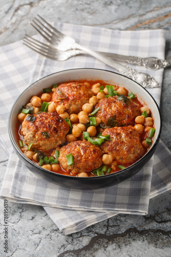 Middle Eastern Lamb meatballs with chickpeas in tomato sauce close-up in a bowl on the table. Vertical
