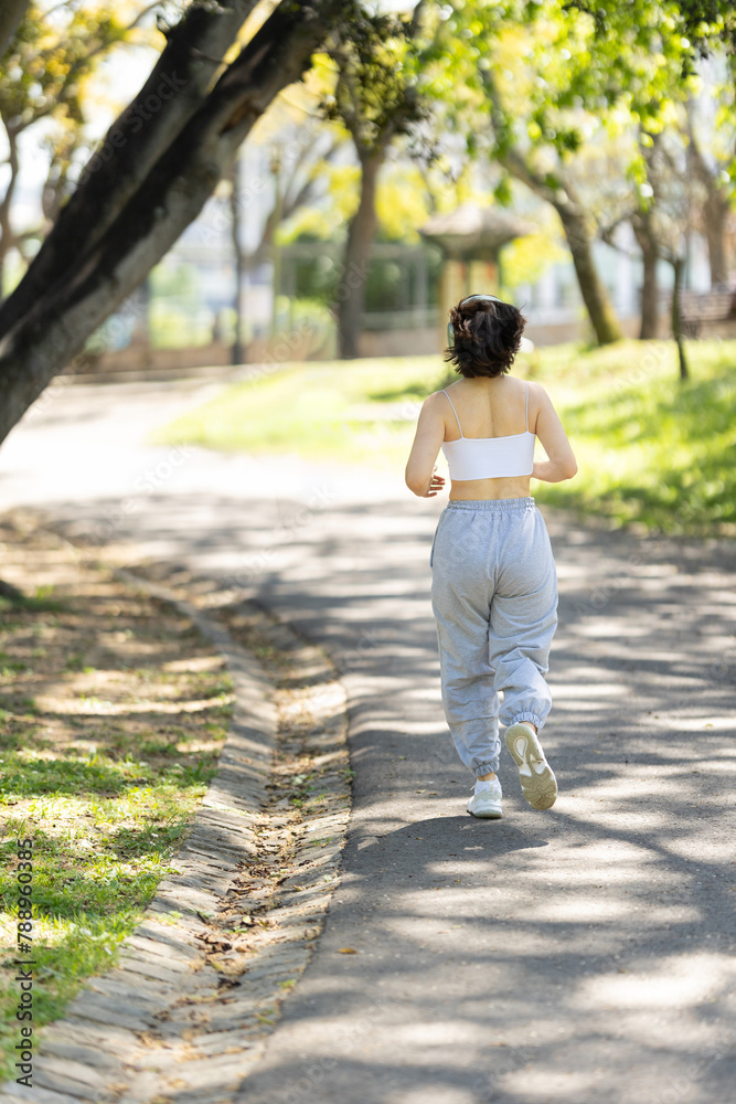 A woman is running on a path in a park A woman is running on a path in a park